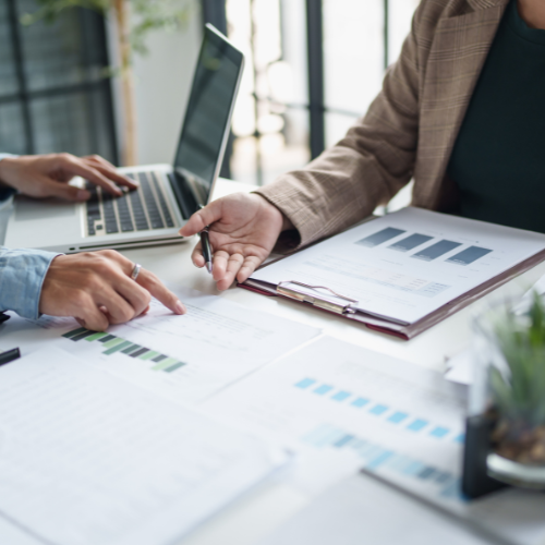 Dos profesionales revisando documentos y gráficas sobre normativa interna y prevención de riesgos corporativos.