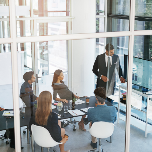 Grupo de profesionales de diversos departamentos en reunión colaborativa en oficina abierta y moderna.